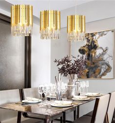 a dining room table set with place settings and gold chandelier hanging from the ceiling