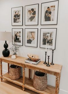 a wooden table topped with pictures next to a lamp