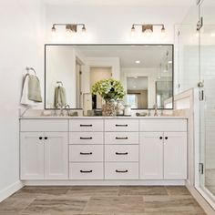 a white bathroom with two sinks and a large mirror on the wall over the bathtub