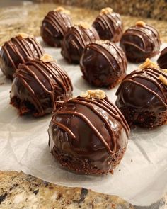 chocolate covered cookies sitting on top of a piece of parchment paper next to a marble counter