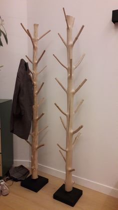 two tall wooden trees sitting next to each other on top of black mats in front of a white wall