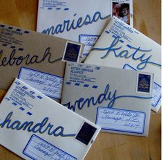 several envelopes with blue ink on them sitting on a wooden table next to each other