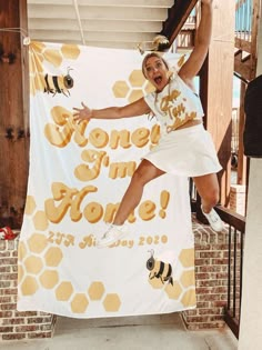 a woman jumping in the air while holding onto a banner with honeycombs on it