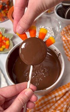 a person dipping candy into a bowl with carrots and candy on the stick in it