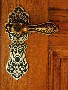 an ornate door handle on a wooden door with black and white designs inlays