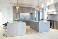 a large kitchen with marble counter tops and stainless steel appliances, along with an island in the middle