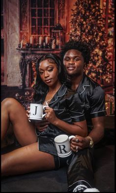 a man and woman sitting next to each other holding coffee cups