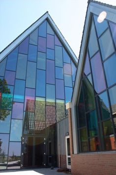 two large glass buildings sitting next to each other in front of a building with windows