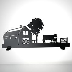 a metal cut out of a farm scene with a cow and barn on the fence