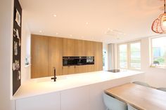 a modern kitchen with an island countertop and wooden cabinetry, along with white walls