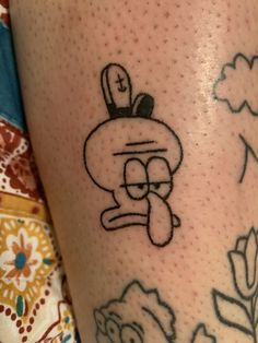 a close up of a person's leg with tattoos on it and an image of a cartoon character