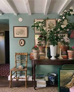 a room with blue walls and pictures on the wall, flowers in vases and a chair