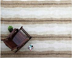 a wooden rocking chair sitting on top of a rug next to a small green plant