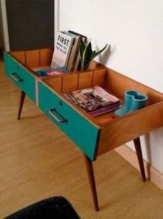 a wooden table with magazines and cups on it in front of a white wall next to a door