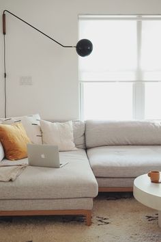 a living room with a couch, coffee table and laptop