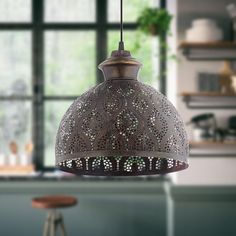 an ornate light fixture hanging from a kitchen ceiling over a bar stool in front of a window