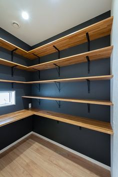 empty shelves in the corner of a room with wood flooring and dark blue walls