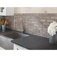 a kitchen counter with a sink, faucet and flowers in a bucket on it