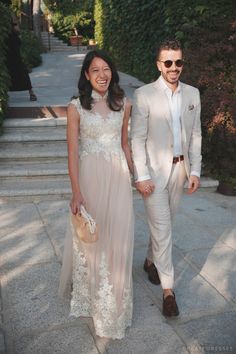 a man and woman in formal wear walking down the street holding hands with each other