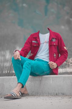 a man in red jacket and blue pants sitting on cement wall with his feet crossed