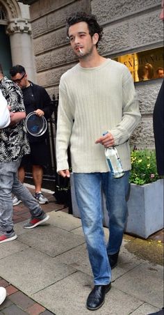 a man walking down the street with a beer in his hand