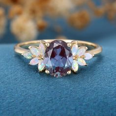 a ring with an oval shaped purple stone surrounded by white opal and gold accents