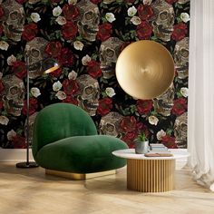 a green chair sitting in front of a wall with skulls and roses on it next to a lamp