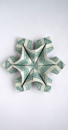 an origami snowflake made out of one hundred dollar bills on a white background