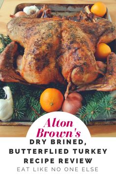 a roasted turkey on a platter with oranges and onions in the foreground text reads alon brown's dry brine, buttered turkey recipe review eat like no one else