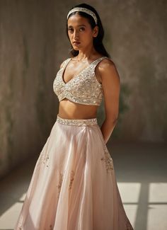 This exquisite Champagne Pink Embroidered Lehenga Set showcases a timeless blend of elegance and craftsmanship. Crafted from luxurious pure satin silk organza, the flowing champagne pink lehenga features stunning hand-embroidered motifs that add a touch of artistic allure to the piece. Paired with a matching blouse, it boasts intricate embroidery that highlights the detailed craftsmanship and elegance of the design. Completed with a dupatta adorned with a hand-embroidered border and delicate ruffles at both ends, this ensemble adds a graceful finish to any occasion. Perfect for a bride or bride-to-be on your special day, this outfit promises to make you feel both confident and enchanting, with its seamless blend of traditional artistry and contemporary style. Composition : Lehenga - Pure S Pink Lehenga, Indian Wedding Wear, Silk Organza, Wedding Wear, Silk Satin, Ruffles, Lehenga, Indian Wedding, Contemporary Style