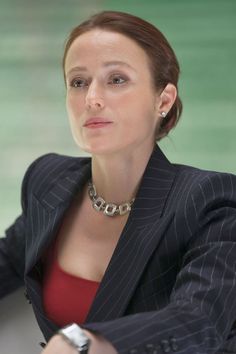 a woman sitting at a table with a watch on her wrist and wearing a suit