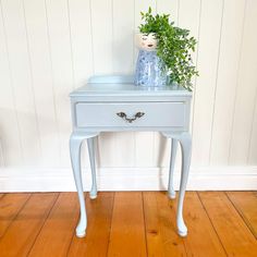 a blue and white table with a plant on it's top next to a wooden floor