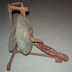 an old metal object sitting on top of a white table next to a wooden spoon