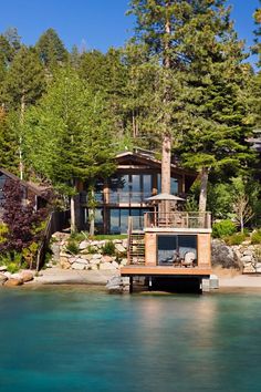 a house sitting on top of a lake surrounded by trees