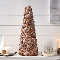 a pine cone christmas tree sitting on top of a table next to plates and candles