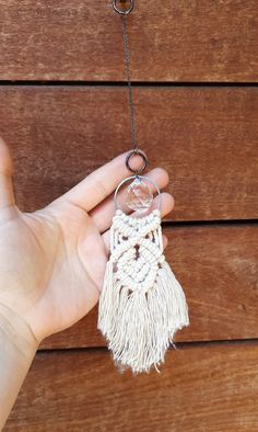 a hand holding a key chain with a tassel hanging from it