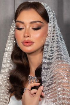 a woman in a wedding dress with a veil on her head and diamond jewelry around her neck