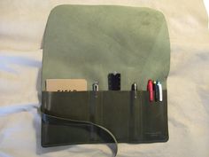 A simple and efficient way to store and keep organized your favourite pens, pencils, and stationery products. Grab a small notebook (moleskine or Field Notes will fit), a couple pens and you're on your way. Want to access an item, simply unroll the case. When you are done, simply roll the case back up and secure with the buckle. If properly cared for, this pen roll should last you a lifetime. --Materials-- Seaweed Green top grain 3-4 oz 99% veg tan leather and nickel plated rivet, nickel plated Green Organizers With Pen Holders For Daily Use, Green Organizer With Pen Holders For Daily Use, Daily Use Green Organizer With Pen Holders, Leather Organizer With Interior Card Slots, Functional Everyday Organizers With Pen Holders, Functional Everyday Organizer With Pen Slots, Rectangular Stationery With Pen Slots For Everyday Use, Modern Organizers With Pen Holders For Daily Use, Modern Travel Organizers With Pen Holders