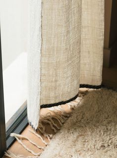 a white rug sitting next to a window on top of a wooden floor