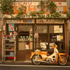 an orange and white motorcycle parked in front of a building with plants growing on it