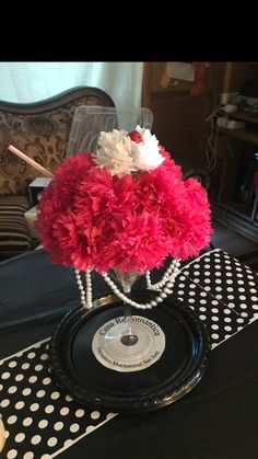 a vase filled with pink and white flowers on top of a black cloth covered table