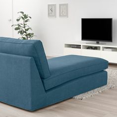 a living room with a blue couch and television on the wall, in front of a white entertainment center