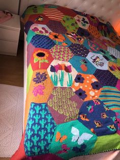 a multicolored quilt on a bed with white headboard and foot board in the background