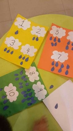 four cards with numbers on them sitting on top of a table in front of a child's hand