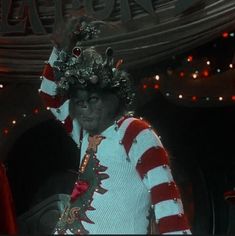 a man dressed up in christmas attire with lights on his head and hands behind his head