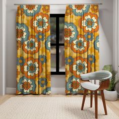 an orange and blue flowered curtain hanging in front of a window with a chair