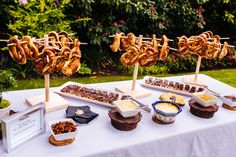 an assortment of food is displayed on a white tablecloth in front of some bushes