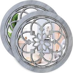 two circular mirrors with decorative designs on the front and back, one in grey wood