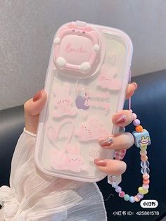 a woman holding up a phone case with charms on it