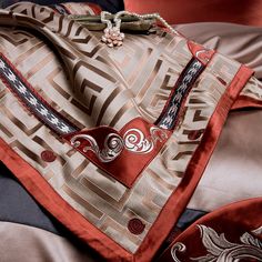 a red and brown bag sitting on top of a bed next to a black pillow